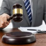 Closeup shot of a person holding a gavel on the table